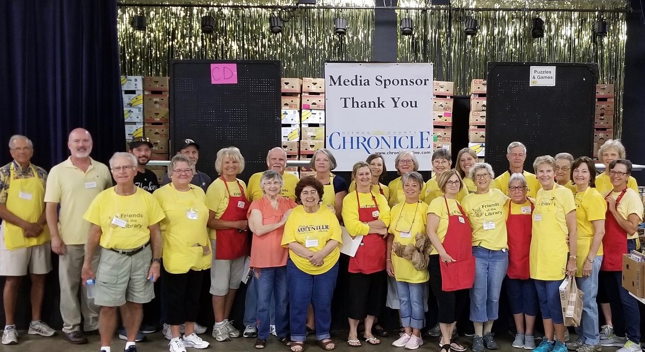 Group of Friends of the Citrus County Library System in front of stage at a book sale