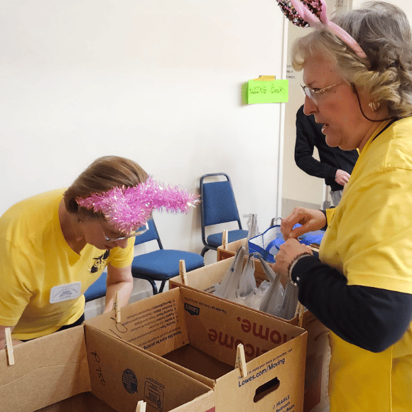 Friends at the booksale 2 Friends of the Library in yellow shirts look over empty boxes of books